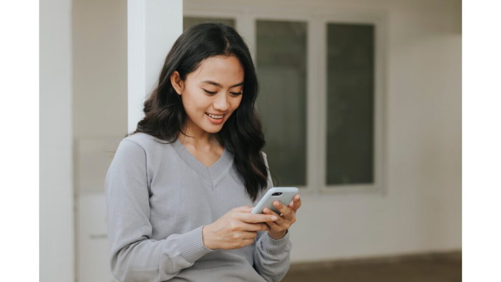 別室から子供のレッスンをスマホで見ている母親